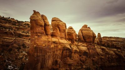 Slickrock pillars stand against a stormy sky.